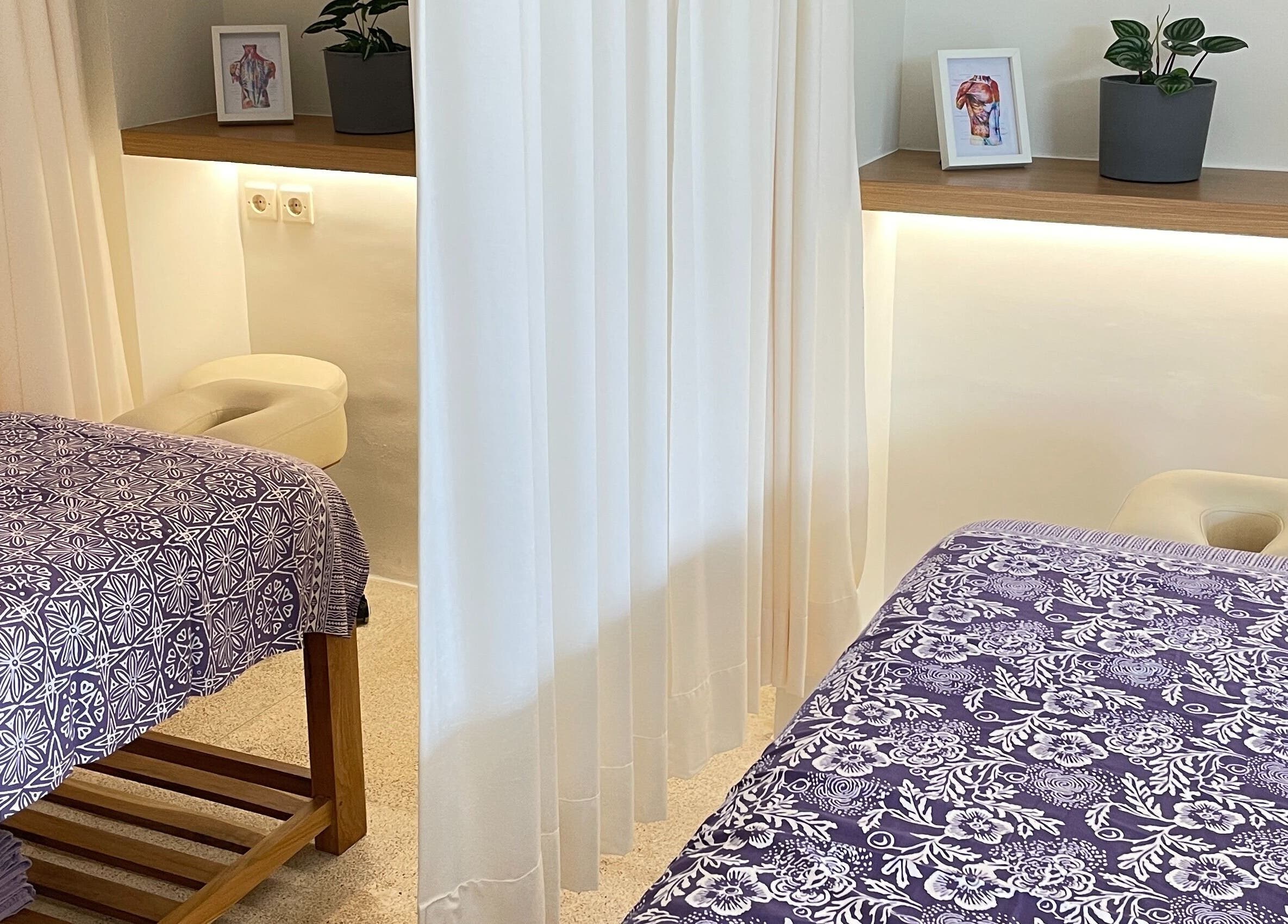 Relaxing massage room at Muscle Works, Bali, Bali, ID with purple floral sheets and calming decor.