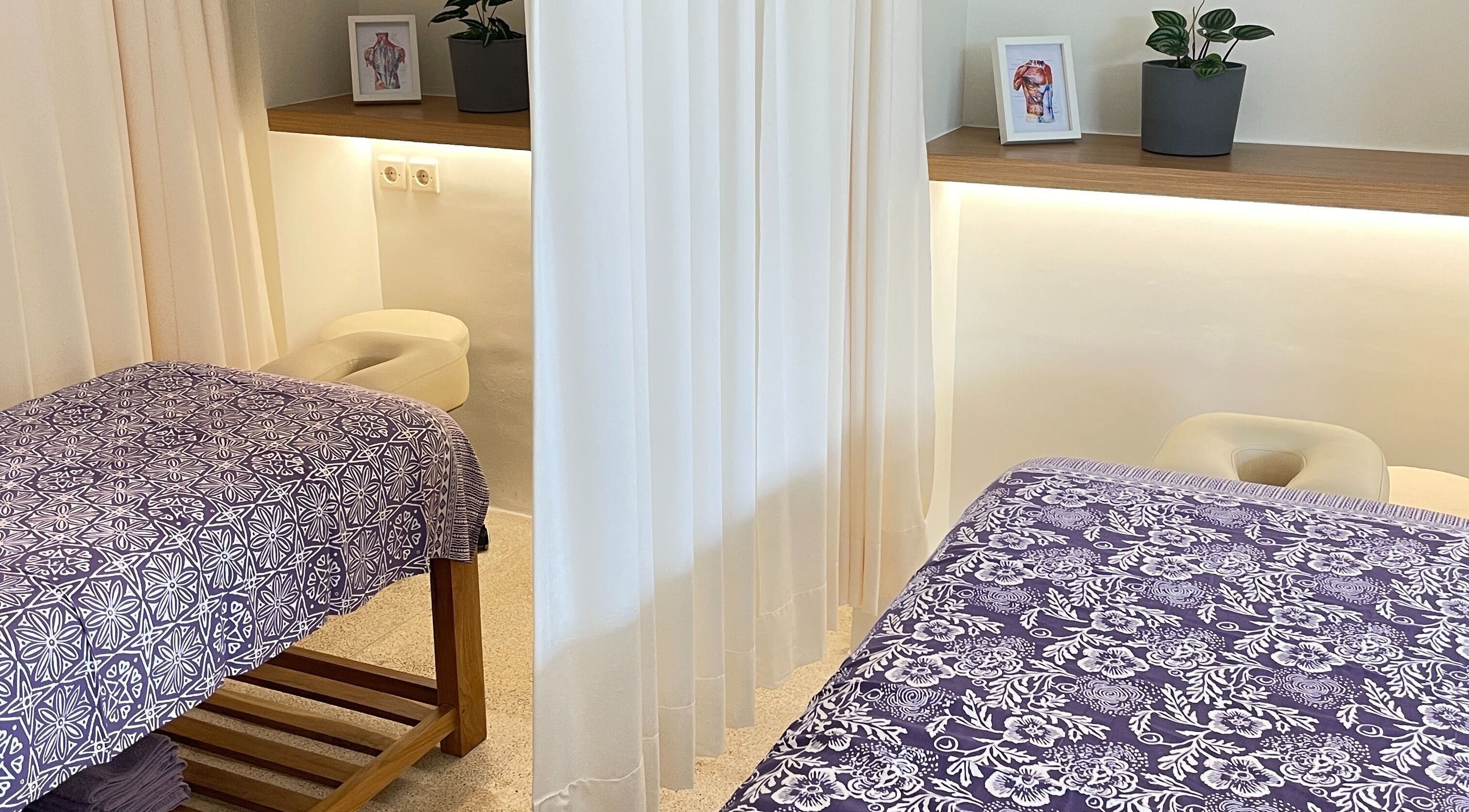 Relaxing massage room at Muscle Works, Bali, Bali, ID with purple floral sheets and calming decor.