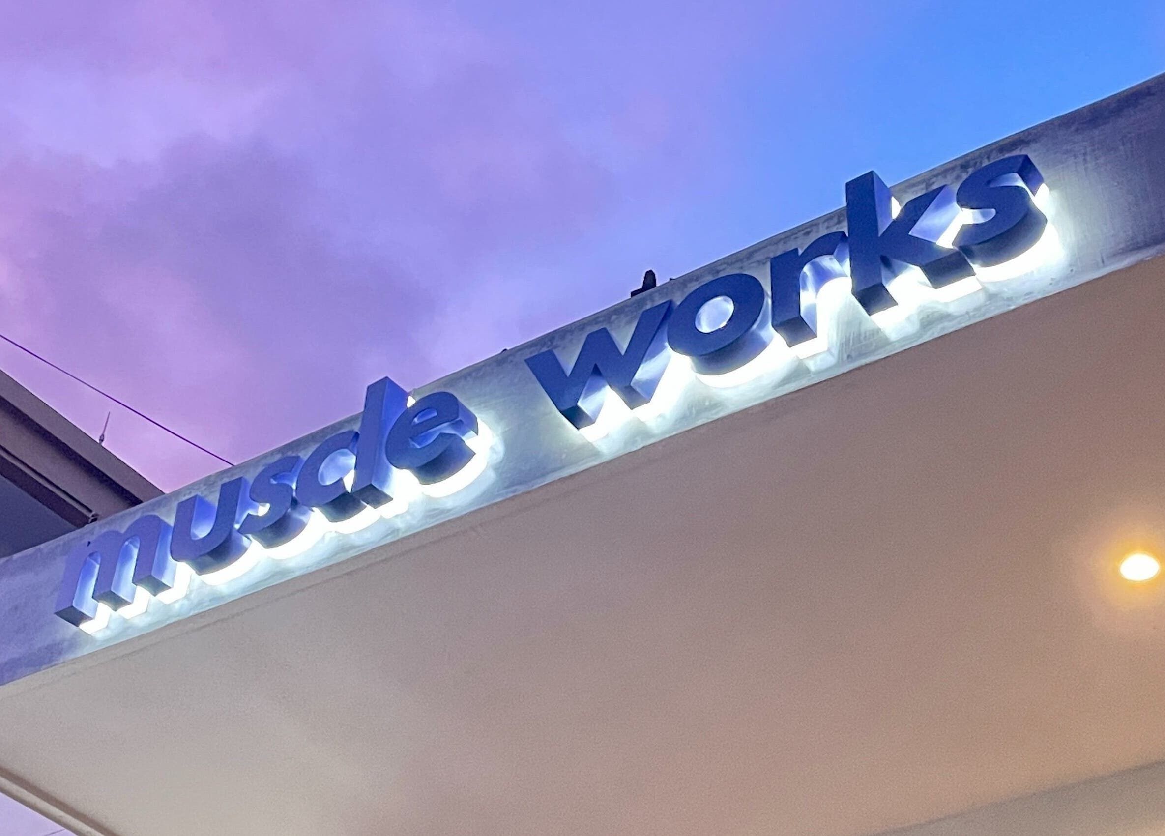 Illuminated Muscle Works sign at twilight, located in Bali, Bali, ID.