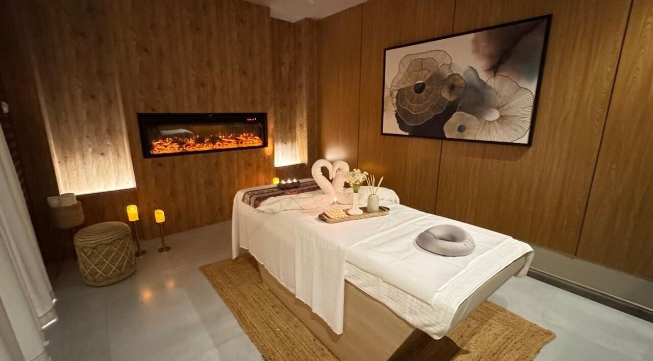 Elegant spa room at Vitaro Spa | Men, Riyadh. Cozy ambiance with candles and artwork on wood panel walls.