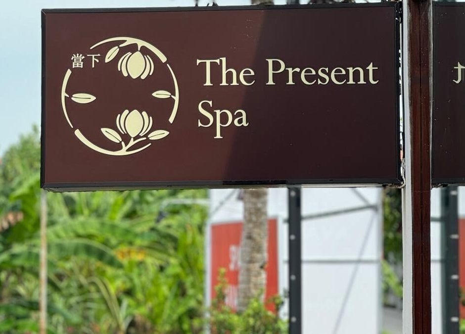Entrance sign of The Present Spa in Bali, Bali, ID with a serene logo and lush greenery backdrop.