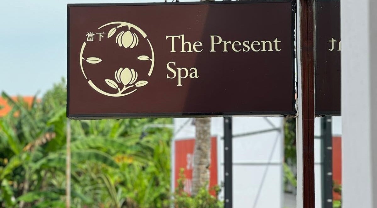 Entrance sign of The Present Spa in Bali, Bali, ID with a serene logo and lush greenery backdrop.