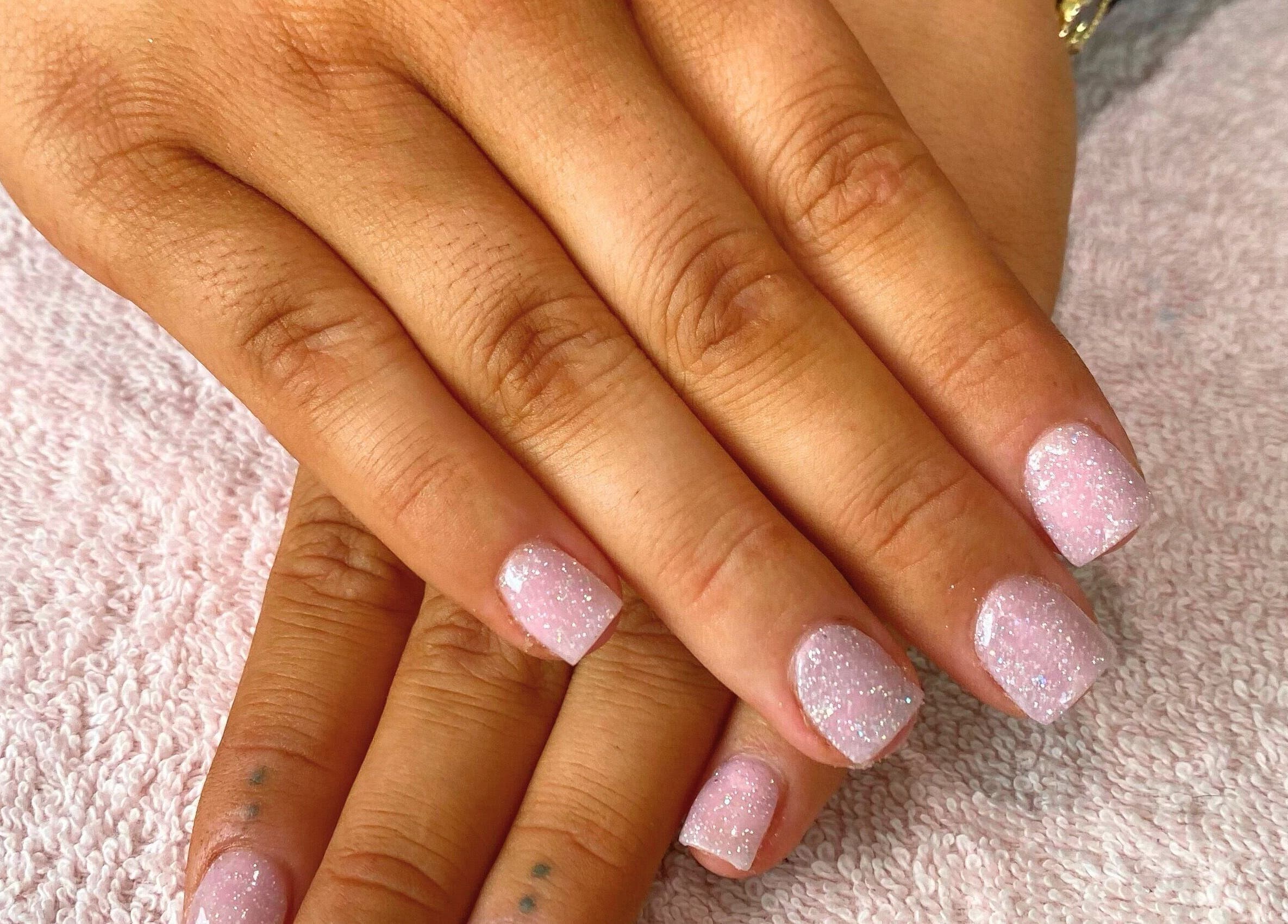 Sparkling pink nails on display at Beauty_by_marni, Fen Street, England, GB.