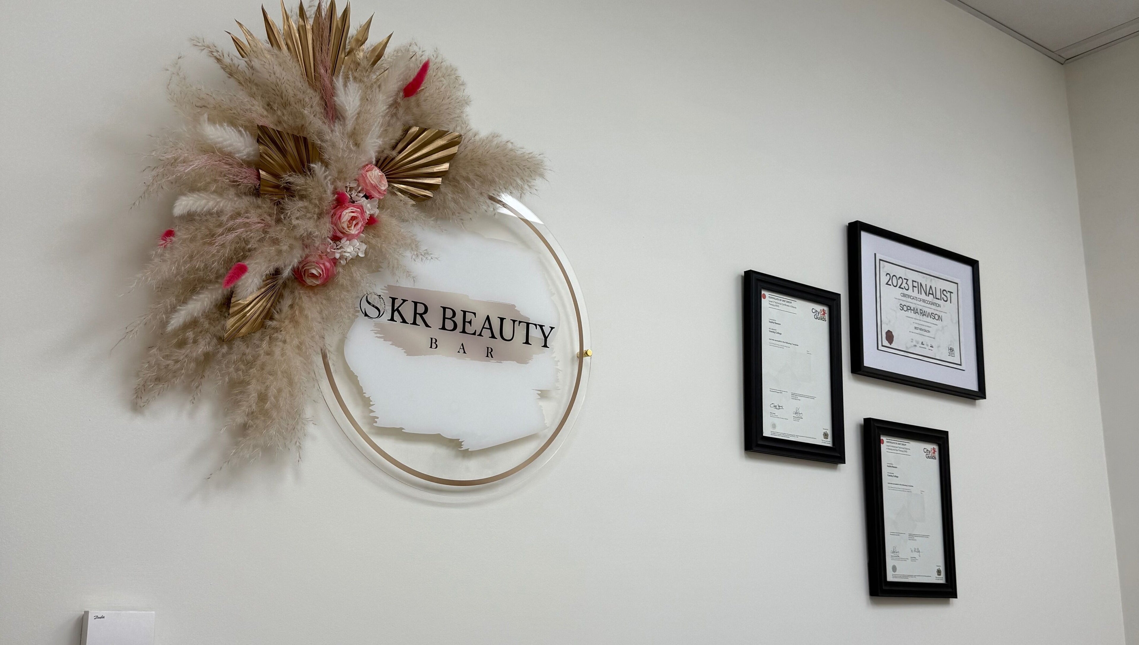 Elegant wall decor with floral accents at SKR Beauty Bar, Broadbridge Heath, England, GB. Award certificates displayed.