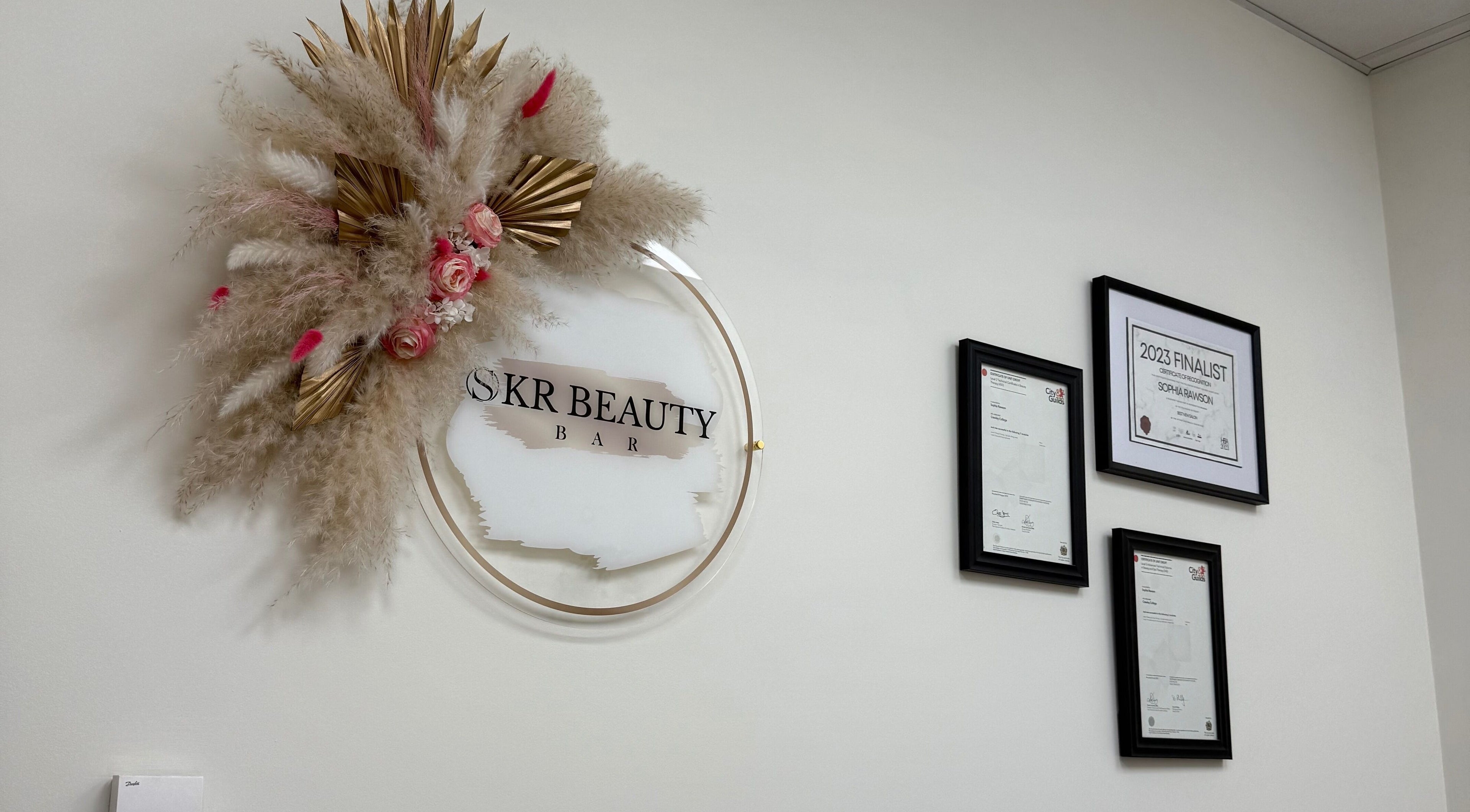 Elegant wall decor with floral accents at SKR Beauty Bar, Broadbridge Heath, England, GB. Award certificates displayed.