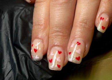 Heart-themed nail design at Lvy Luxe Nails, Swindon, England, GB. Red and pink hearts on clear nails.