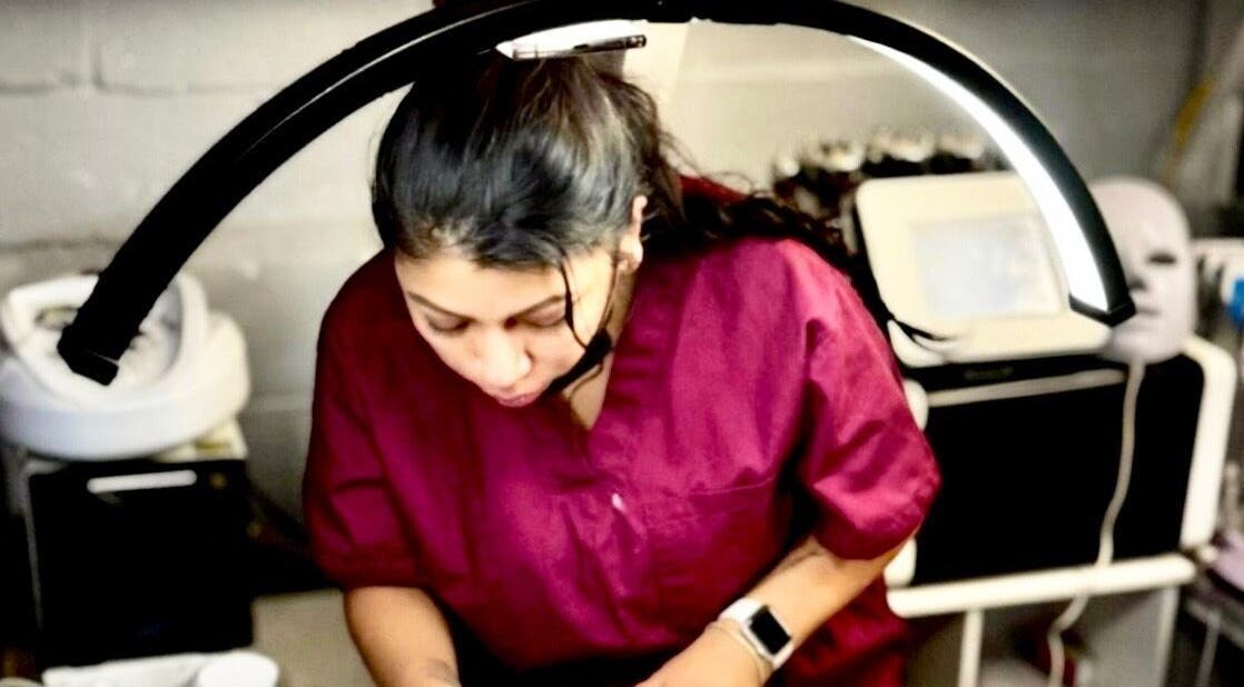 Aesthetician at Diamond Glow in Malden, Massachusetts, US, focusing under a treatment light.