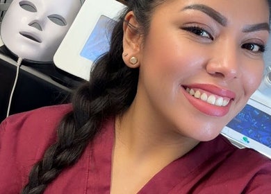 Smiling beauty technician at Diamond Glow, Malden, Massachusetts, US, with skincare equipment in the background.