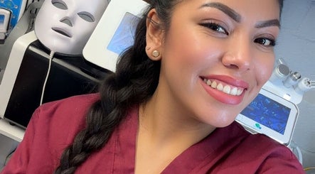 Smiling beauty technician at Diamond Glow, Malden, Massachusetts, US, with skincare equipment in the background.