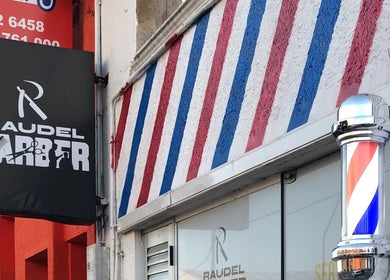 Fachada de Raudel Barber en Maldonado con emblema clásico de barbería y diseño en rayas.