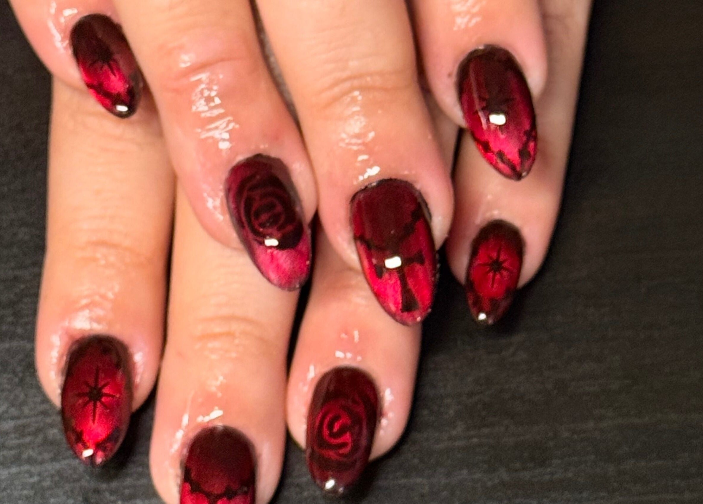 Elegant red gothic nail art from Opal & Claws, Hurst, Texas, US, showcasing intricate rose and cross designs.