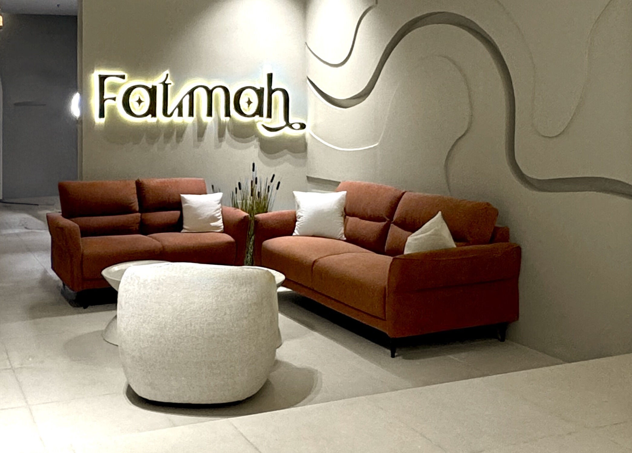 صالون أنيق في Fatimah Beauty Artist بالقطيف, SA مع أرائك برتقالية وديكور مميز.