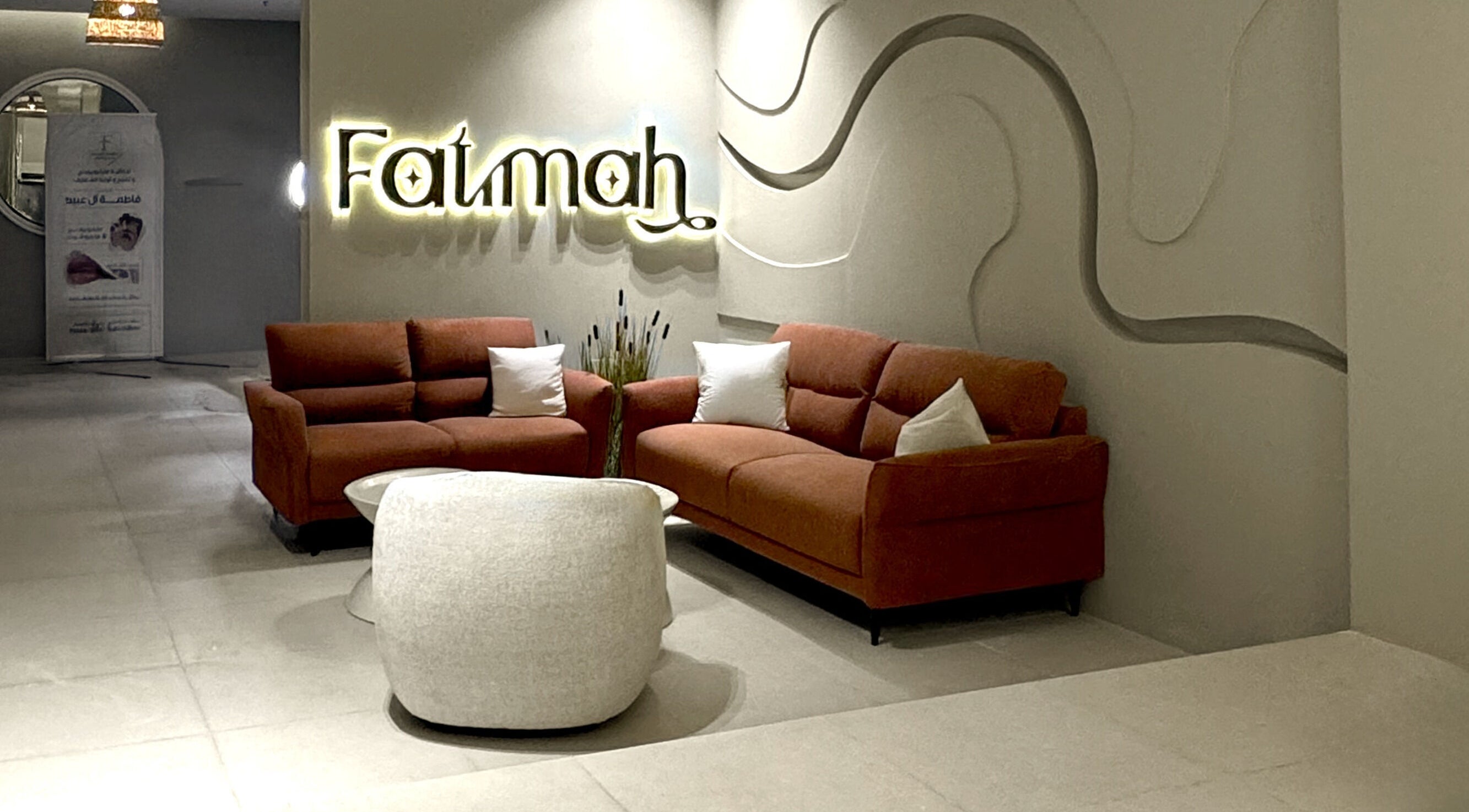 صالون أنيق في Fatimah Beauty Artist بالقطيف, SA مع أرائك برتقالية وديكور مميز.