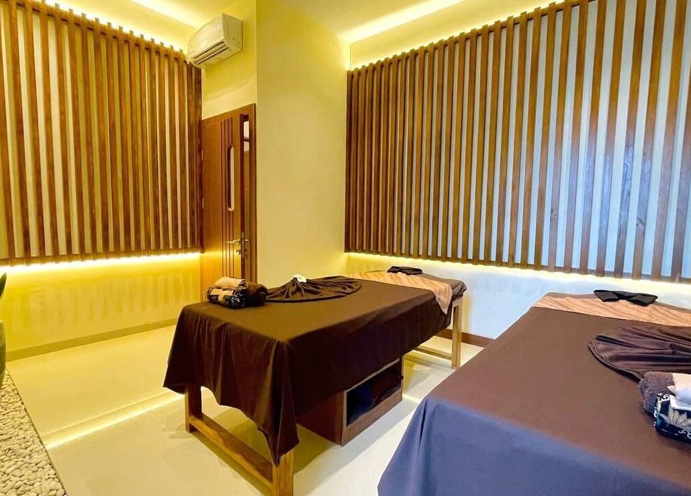 Spa Central Baloi massage room in Kepulauan Riau features tranquil ambiance with warm lighting and wooden accents.