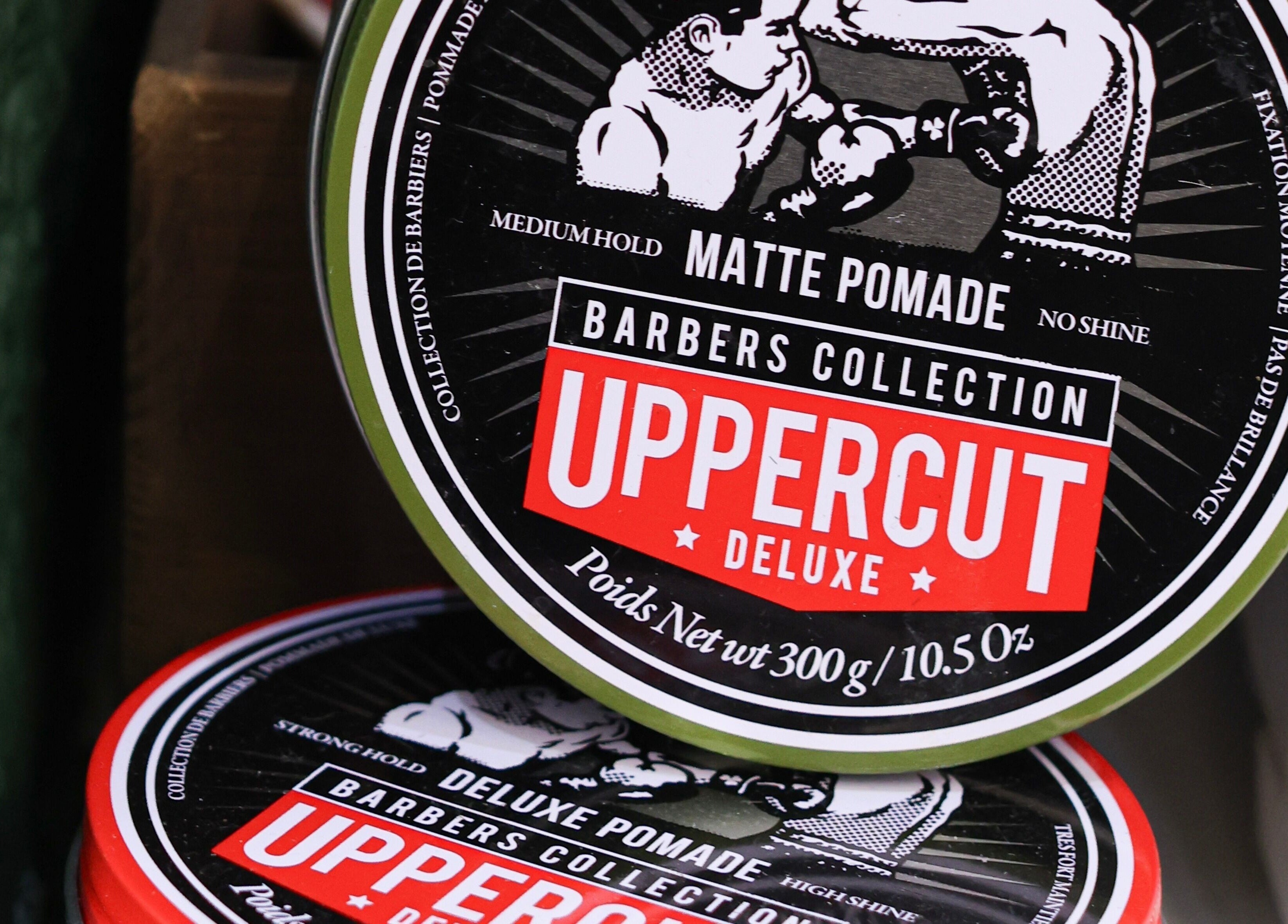 Uppercut Deluxe pomade displayed at Hairport, Bushey, England, GB, showcasing a vintage design.