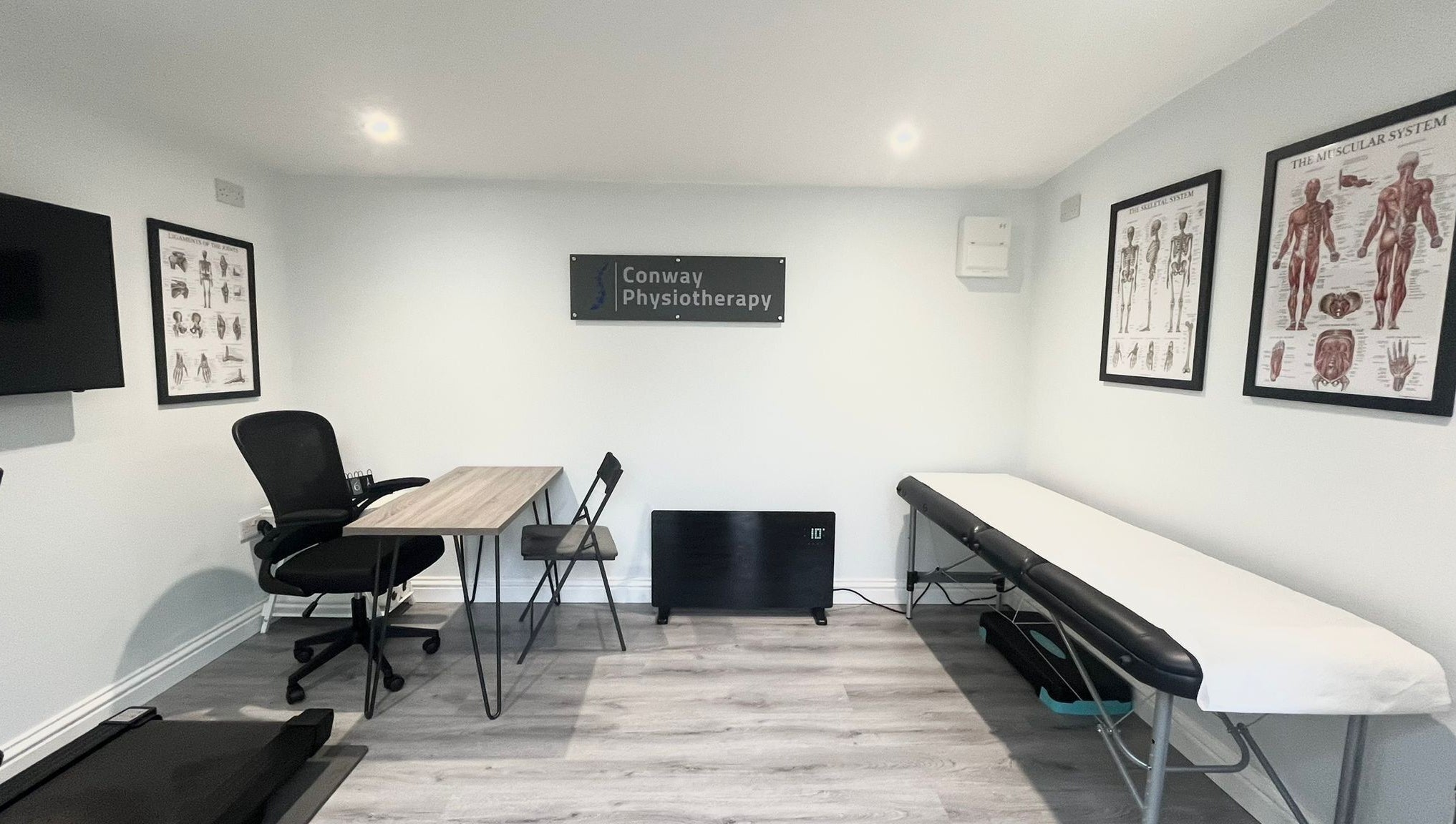 Interior of Conway Physiotherapy in Ratby, England, GB featuring a therapy table and anatomical posters.