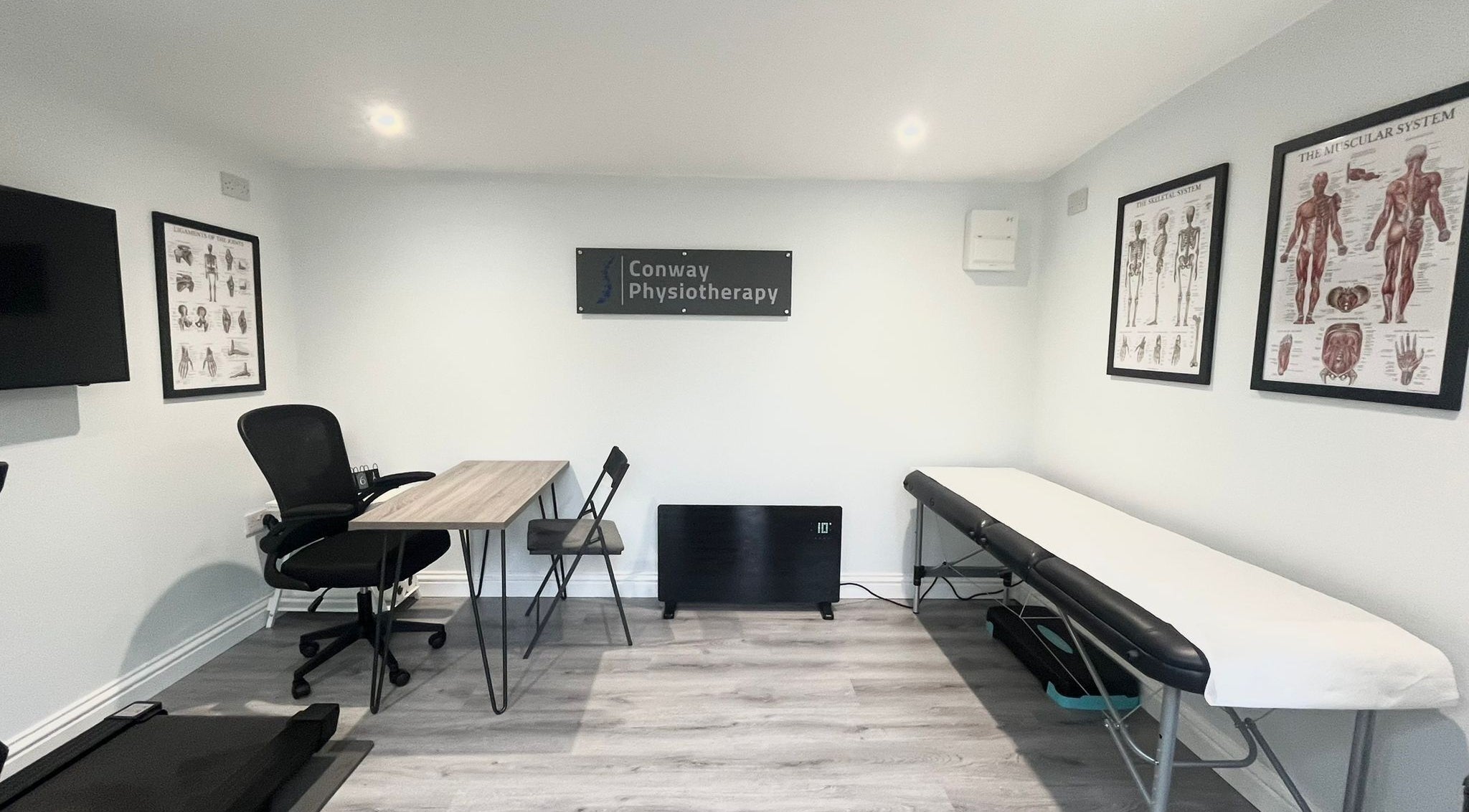 Interior of Conway Physiotherapy in Ratby, England, GB featuring a therapy table and anatomical posters.