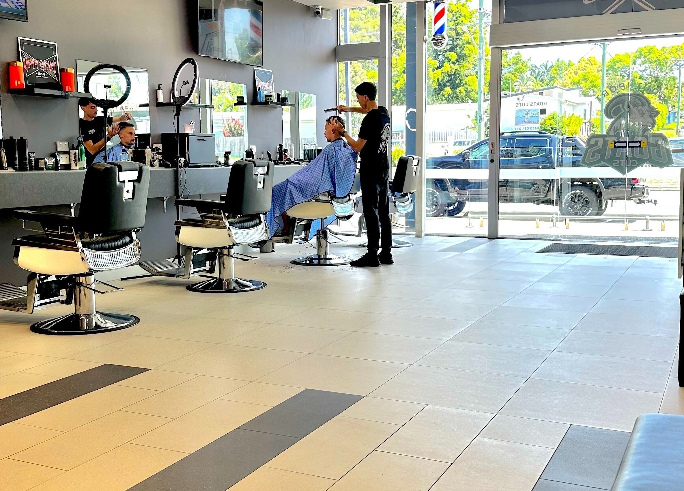 Modern barber setup at Goats Cuts, Southport, Queensland, AU, with stylists and clients.