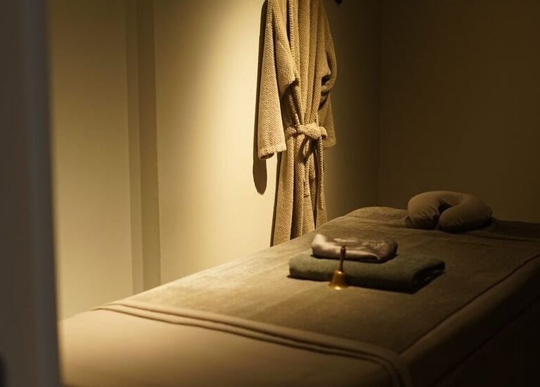 Tranquil massage room at XINGSPA, กรุงเทพมหานคร, TH with a cozy robe on the wall.