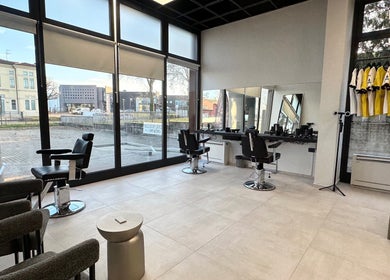Interno moderno di AVELINO Barbershop CENTRO a Parma, Emilia-romagna, IT con ampie finestre e poltrone da barbiere.