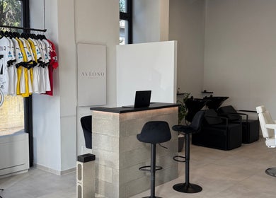 Interno moderno di AVELINO Barbershop LEMIGNANO a Lemignano, Emilia-romagna, IT con sedie e banchi eleganti.