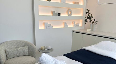 Elegant treatment room at Cathy’s Ideal Beauty Clinic, Gladesville, NSW, AU. Features cozy seating and backlit shelves.