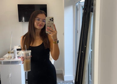 Woman in Beauty by Billie salon, Portsmouth, England, taking a mirror selfie holding a drink.