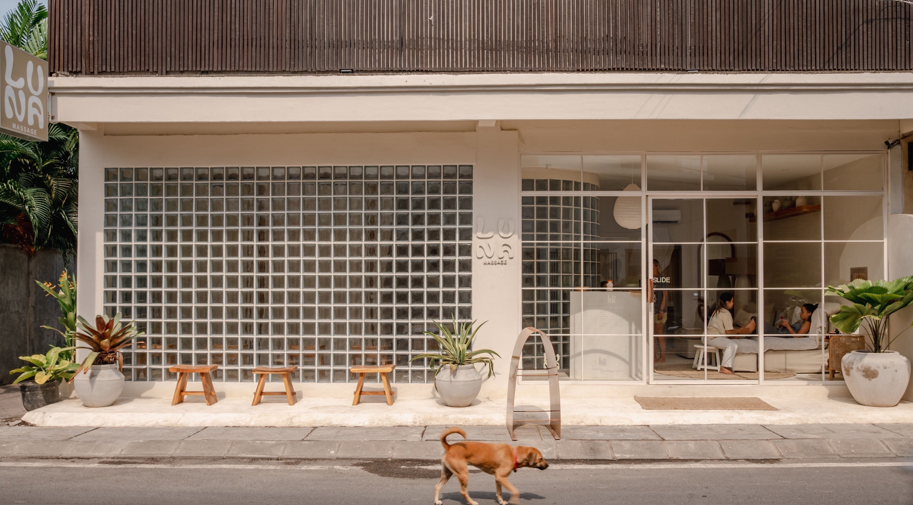 Entrance of Luna Massage Seseh in Bali, showcasing a welcoming facade with glass blocks and plants.
