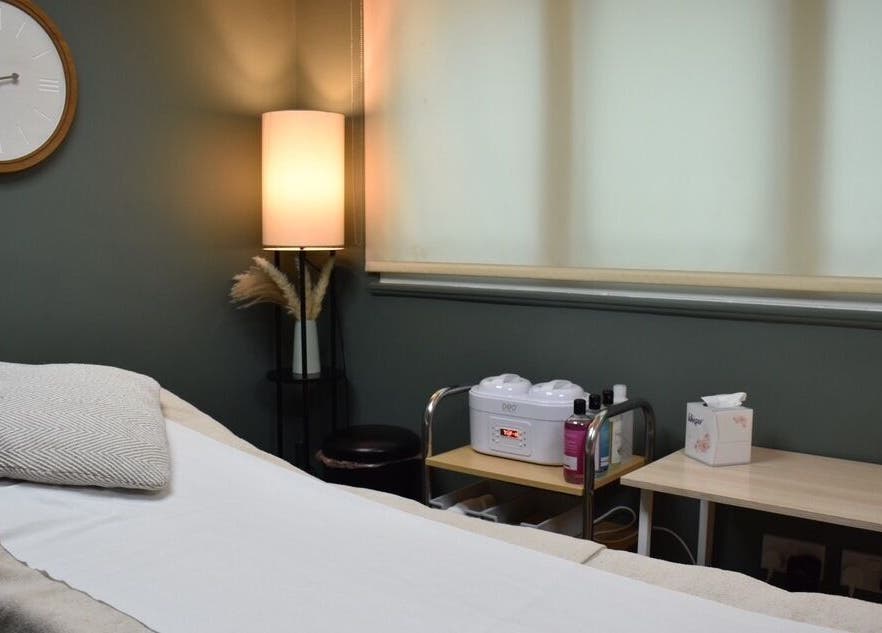 Cozy treatment room at Elite Intimate Waxing in Ruddington, England, GB with bed, warm lighting, and waxing equipment.