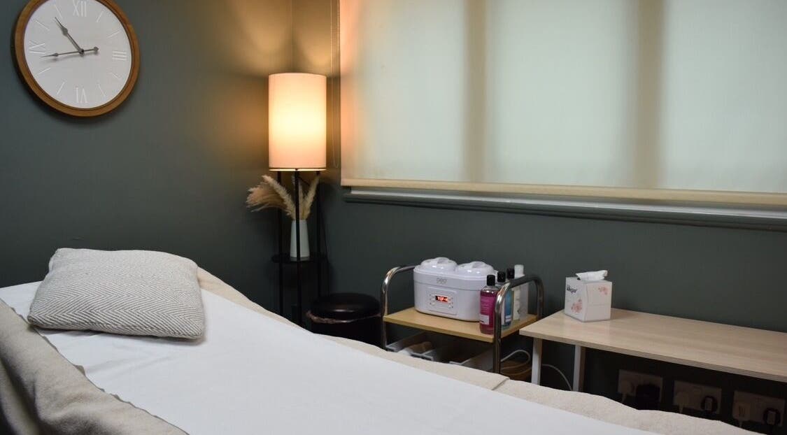 Cozy treatment room at Elite Intimate Waxing in Ruddington, England, GB with bed, warm lighting, and waxing equipment.