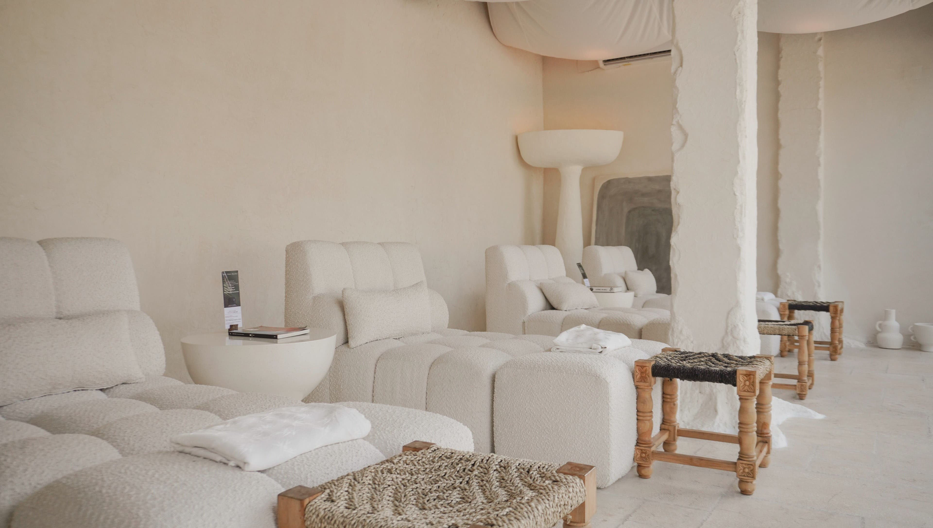 Relaxing lounge at Aetheria Natural Healing Spa in Canggu, Bali, ID, featuring plush white seating and calming decor.