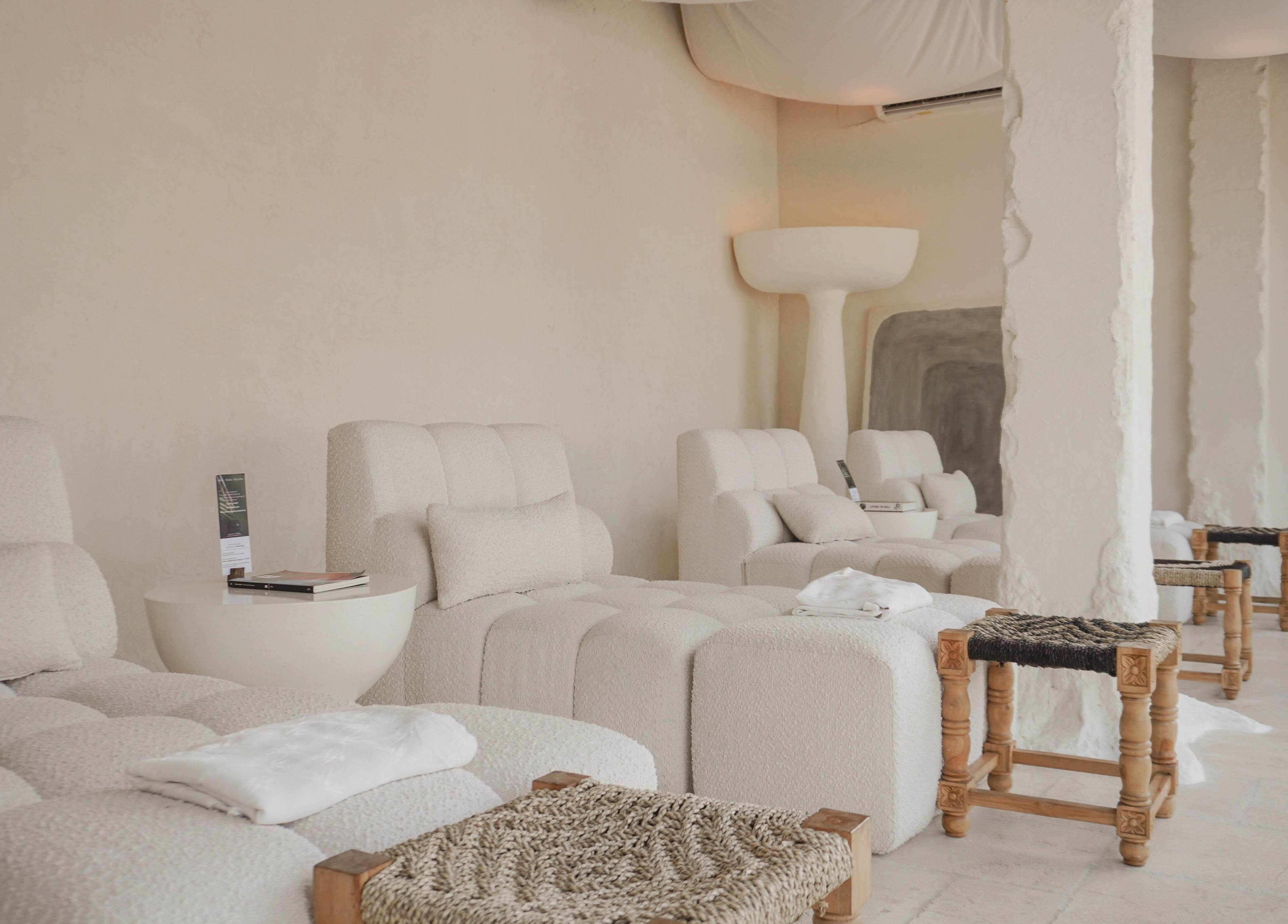 Relaxing lounge at Aetheria Natural Healing Spa in Canggu, Bali, ID, featuring plush white seating and calming decor.