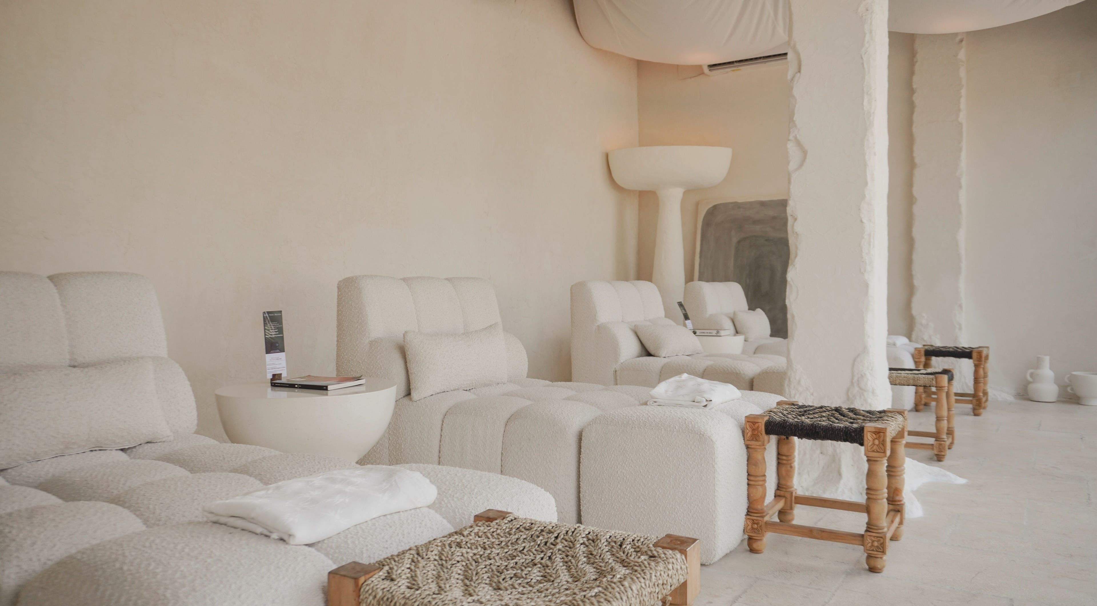 Relaxing lounge at Aetheria Natural Healing Spa in Canggu, Bali, ID, featuring plush white seating and calming decor.