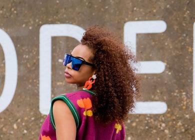Fashionable woman with curly hair at Zulu Bonita, London, England, GB, showcasing vibrant style.
