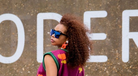 Fashionable woman with curly hair at Zulu Bonita, London, England, GB, showcasing vibrant style.