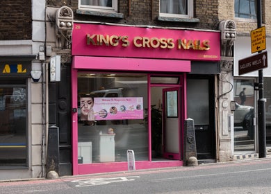 Exterior of Kingscross Nails salon in London, England, GB with a vibrant pink storefront.
