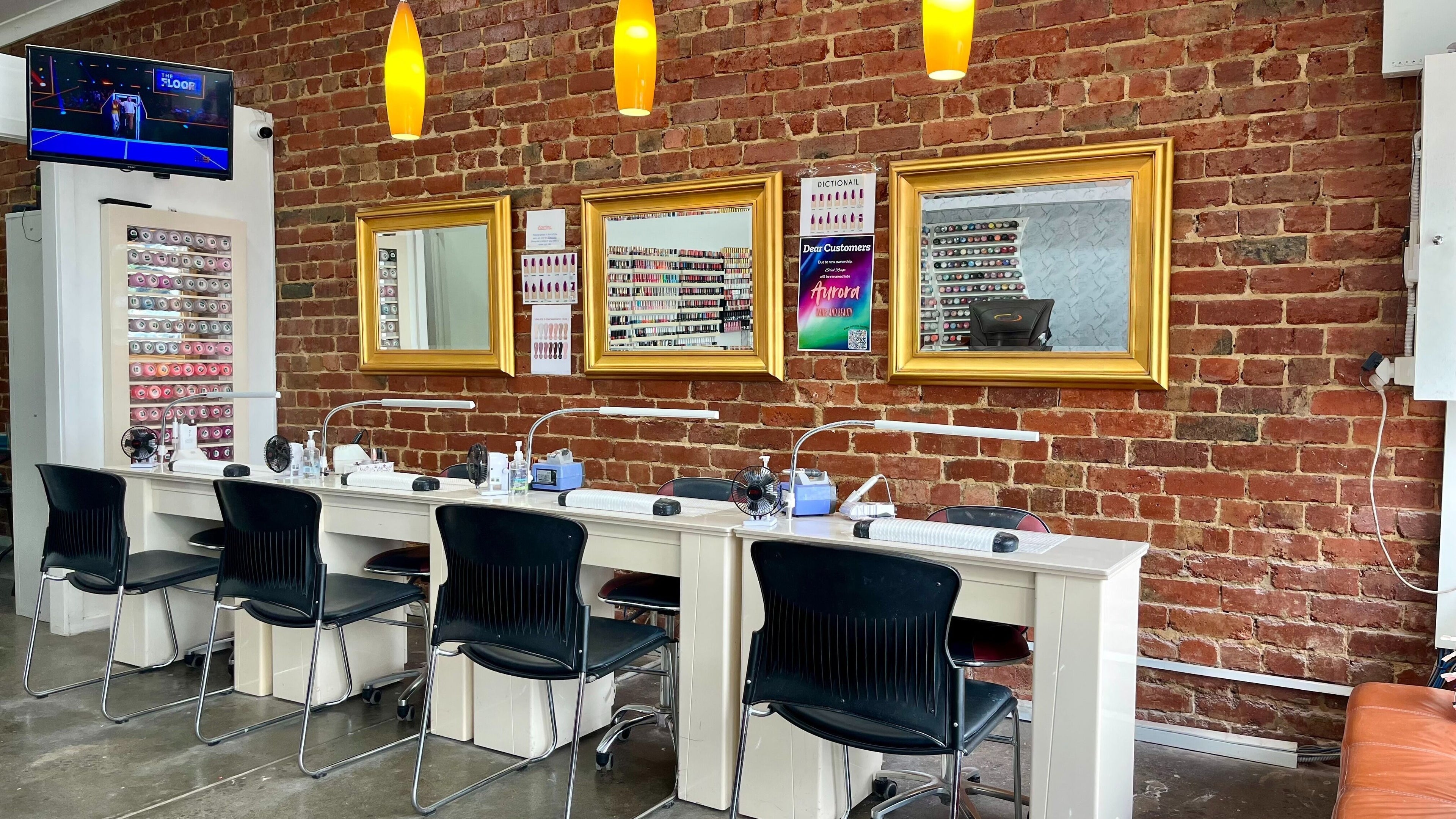 Modern nail stations at Aurora Nails and Beauty | Watsonia in Melbourne, Victoria, AU with warm lighting and brick wall.
