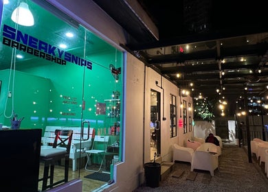 SNEAKYSNIPS BARBERSHOP entrance with seating area in Johor Bahru, Johor Darul Ta'zim, MY under stylish lighting.