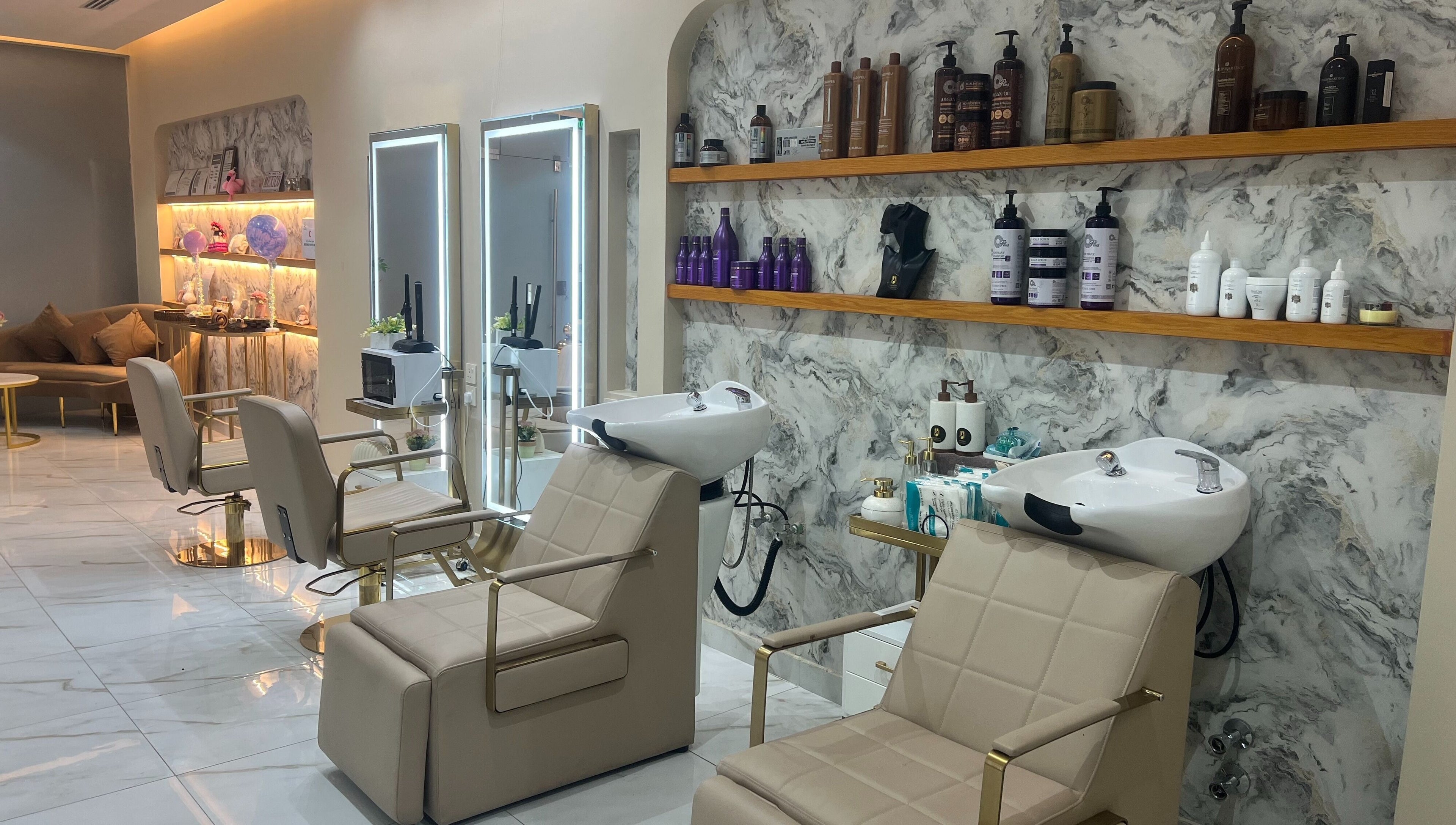 Elegant interior of Wejdan Aljamal Beauty Salon in Dhahran, SA with chic styling chairs and a marble backdrop.