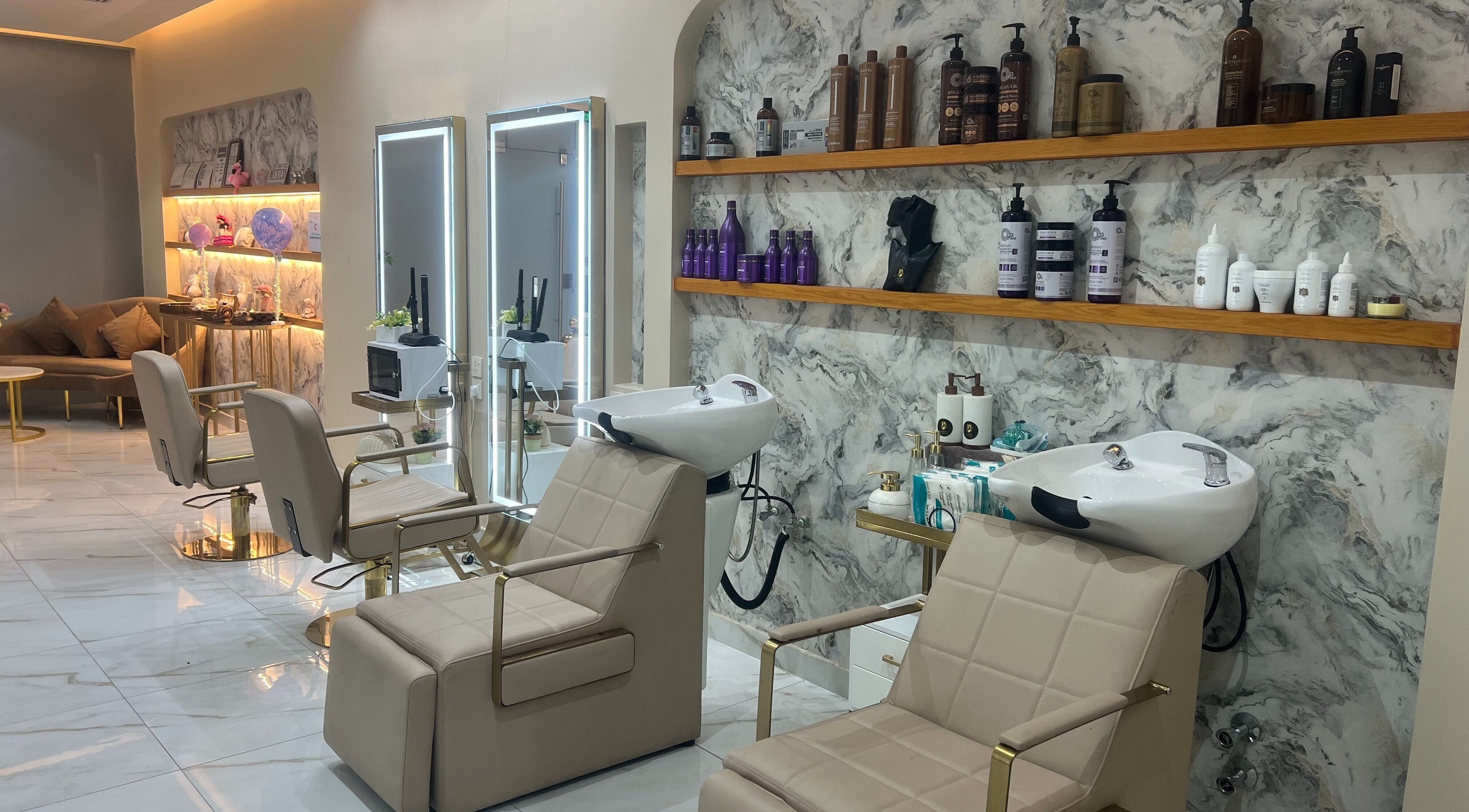 Elegant interior of Wejdan Aljamal Beauty Salon in Dhahran, SA with chic styling chairs and a marble backdrop.