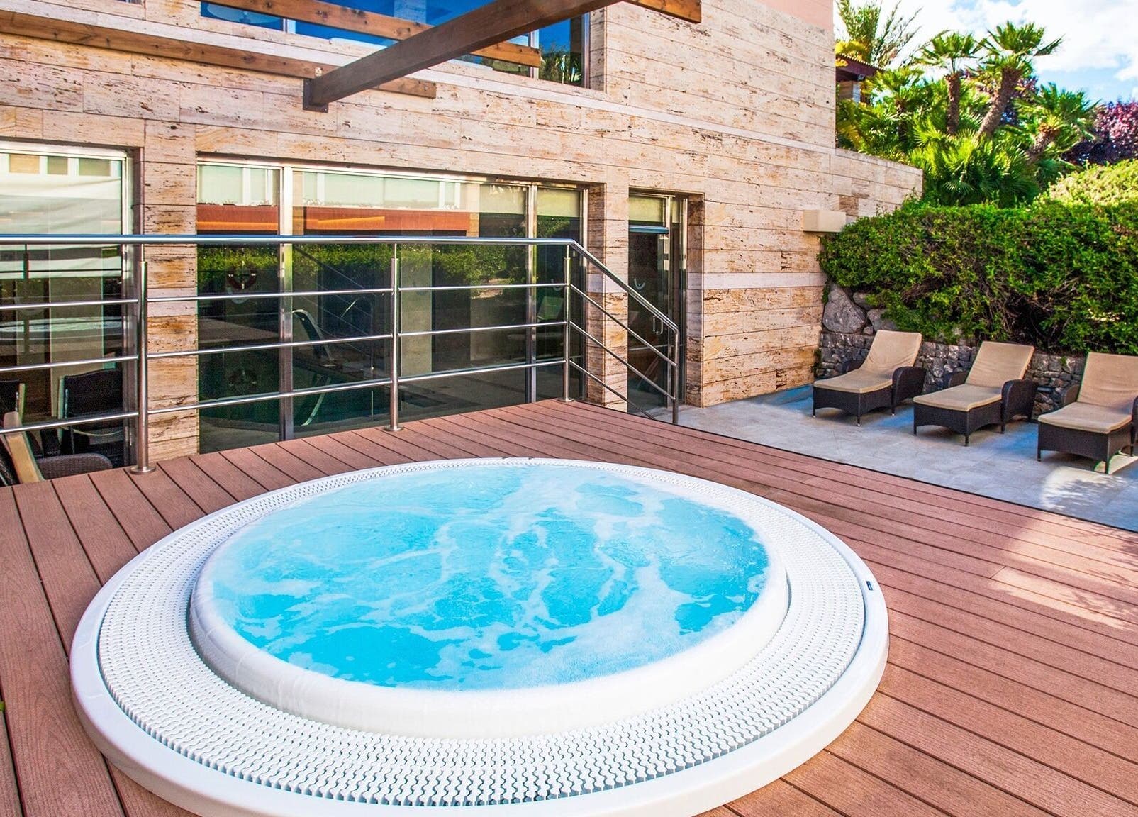Jacuzzi deck at Spa Viva Blue & Spa, Illes Balears, ES, surrounded by sun loungers and greenery.