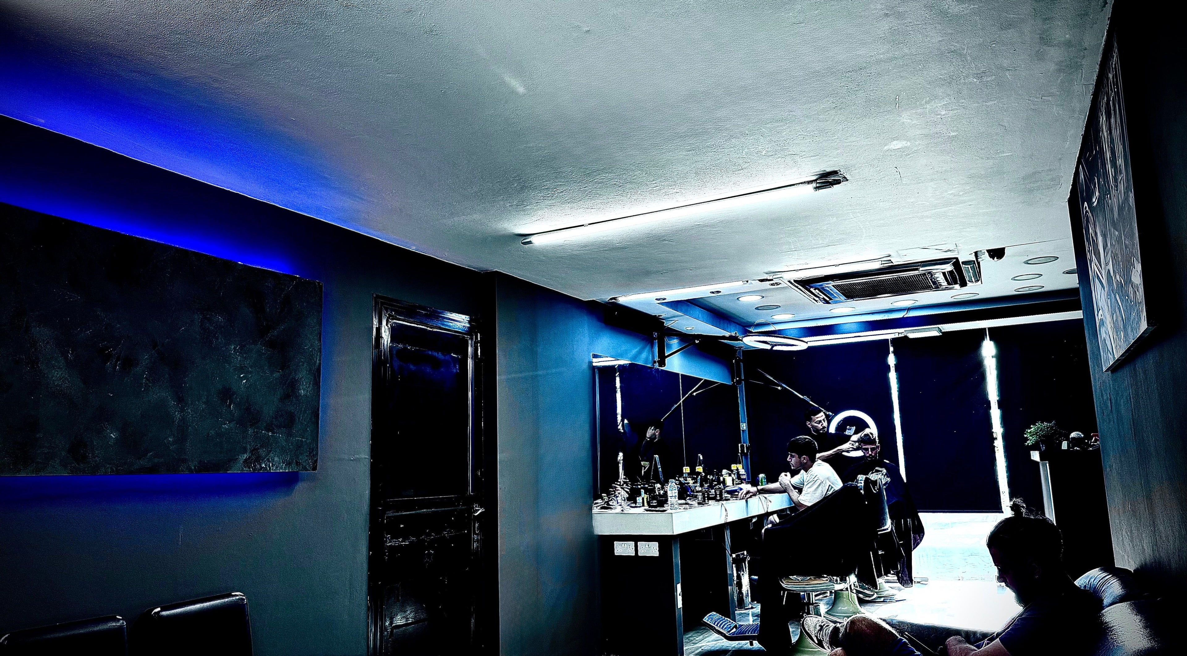 Εσωτερικό του Aggelos Barber Shop στη Λεμεσό, με μοντέρνο φωτισμό και κομμωτή στο έργο.