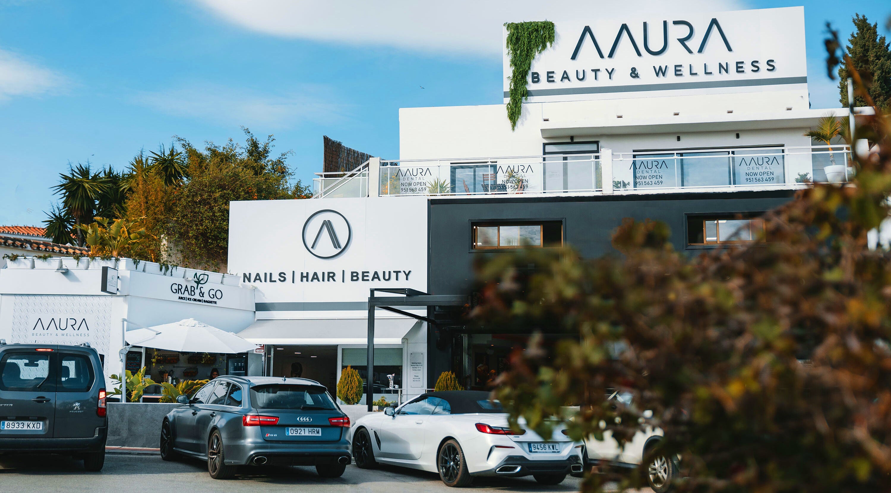 Exterior view of Aaura Beauty & Wellness in Marbella, Andalucía, ES with modern signage and parked cars.