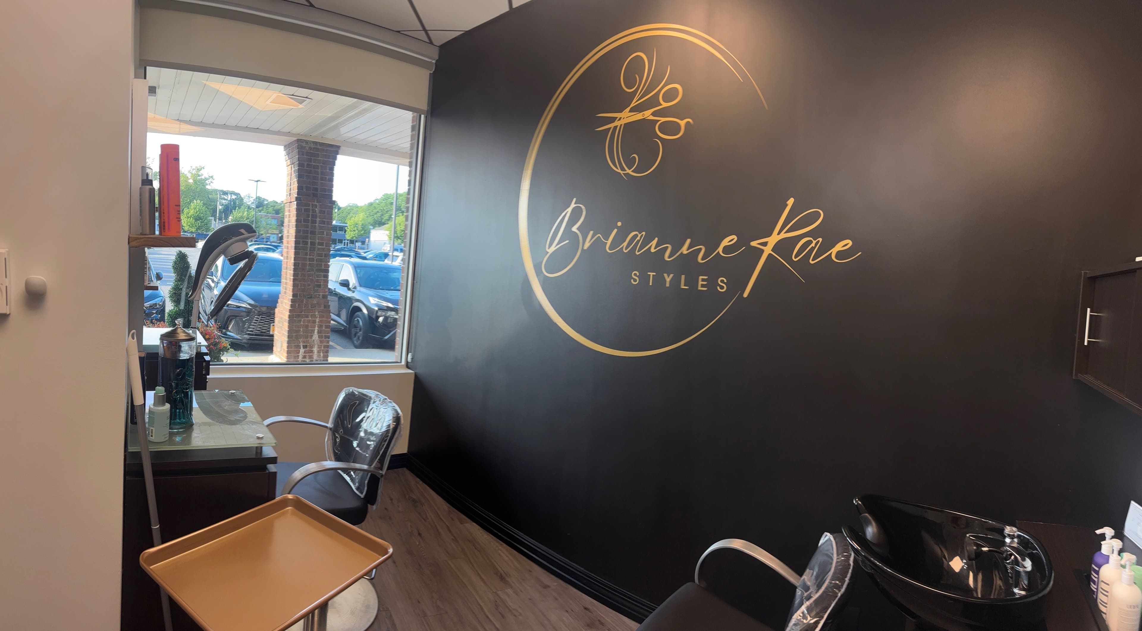 Interior of Brianne Rae styles, Smithtown, New York, US. Elegant salon design with large logo wall.