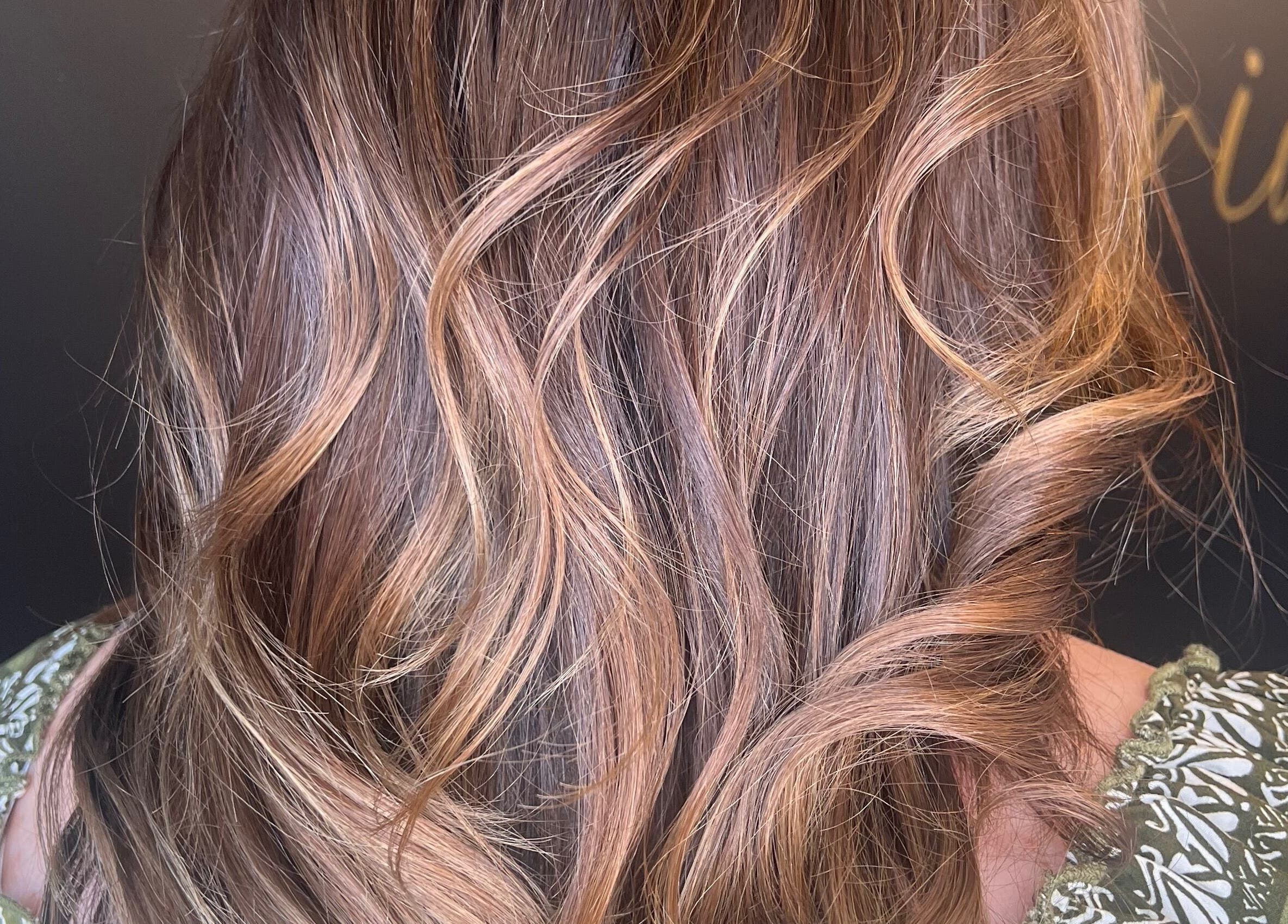 Close-up of wavy hair styled at Brianne Rae Styles in Smithtown, New York, US with rich golden highlights.