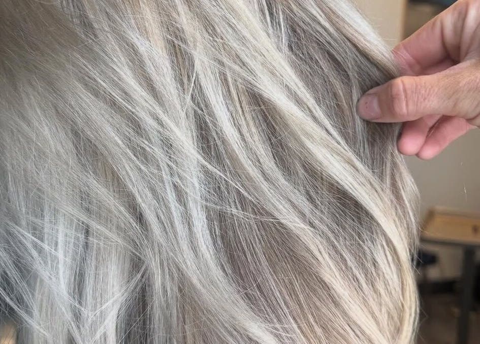 Close-up of a hand holding silver-blonde hair at Brianne Rae Styles in Smithtown, New York, US.