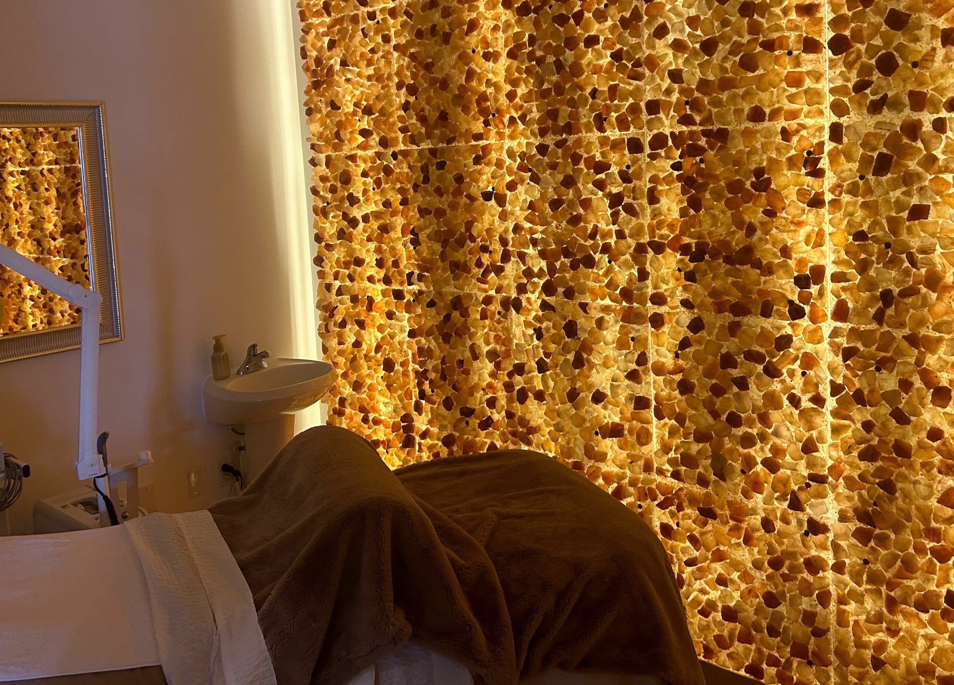 Relaxing massage room at ReVive Spa Charlotte with a warm, glowing stone wall in Charlotte, North Carolina, US.