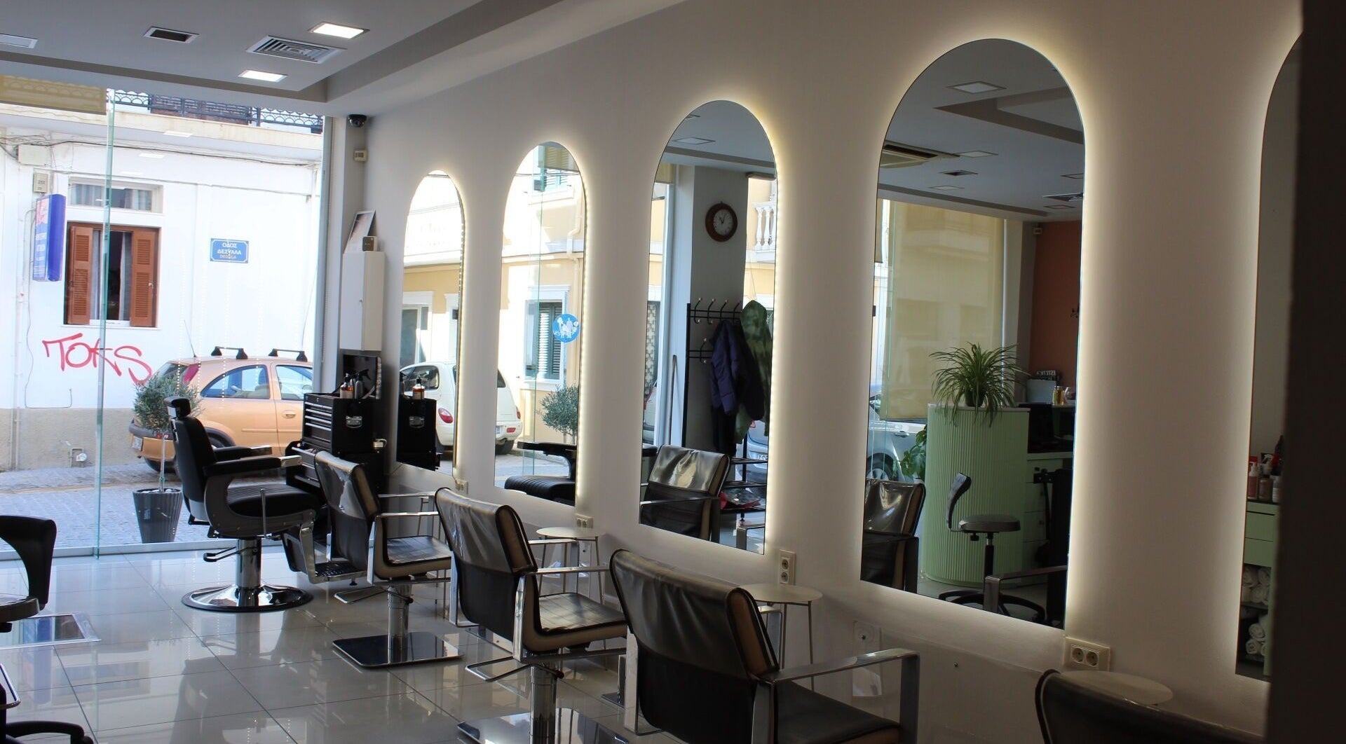 Κομψό εσωτερικό του Hairloom στη Ζάκυνθο, GR με μοντέρνες καρέκλες και φωτισμένους καθρέφτες.