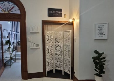 Inviting entrance of True Form Aesthetics in Te Awamutu, Waikato Region, NZ, featuring wood decor and greenery.