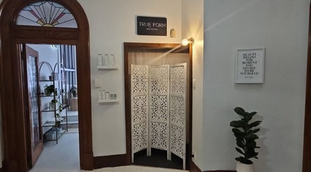 Inviting entrance of True Form Aesthetics in Te Awamutu, Waikato Region, NZ, featuring wood decor and greenery.